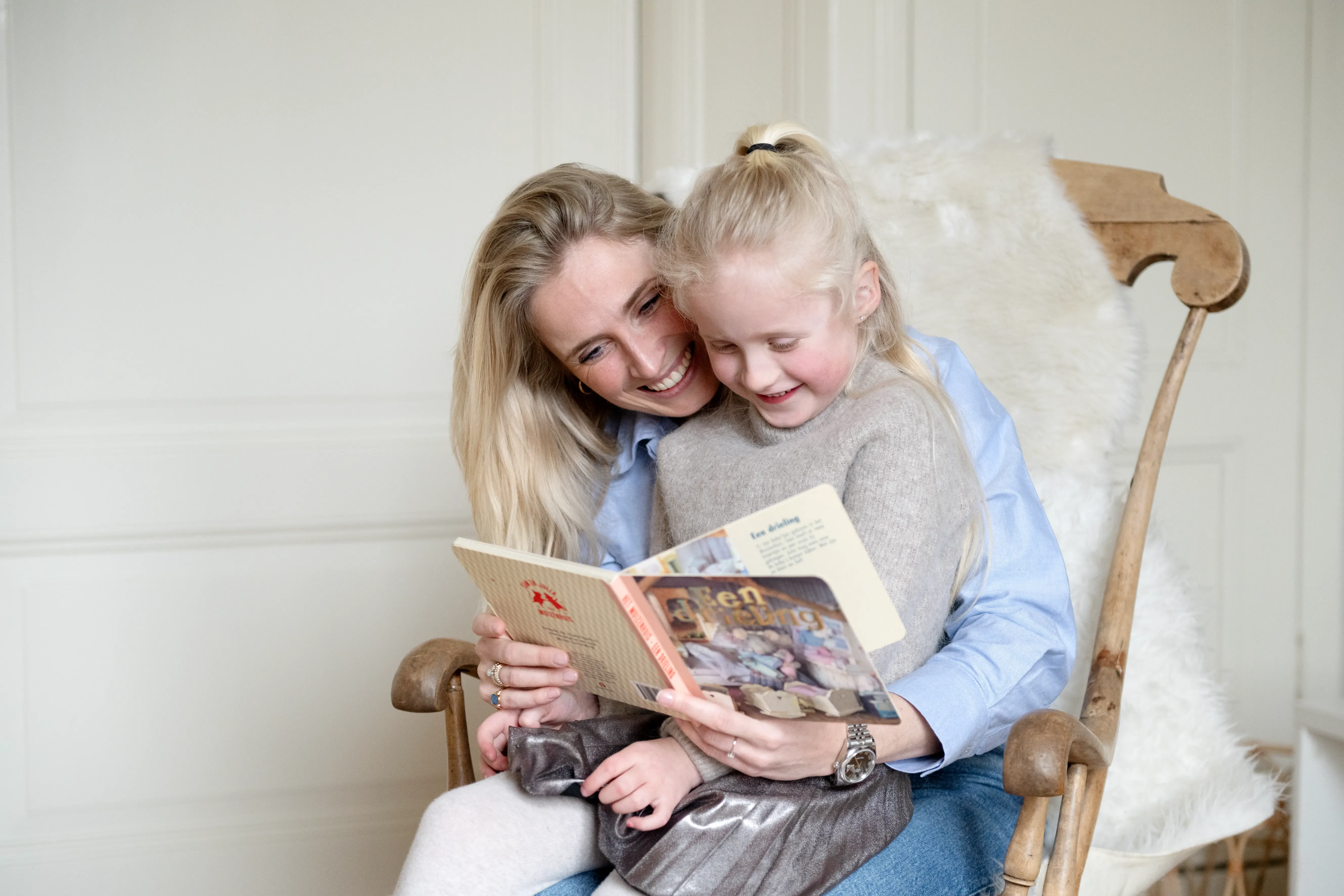 Moeder en dochter samen een boek aan het lezen in wipstoel