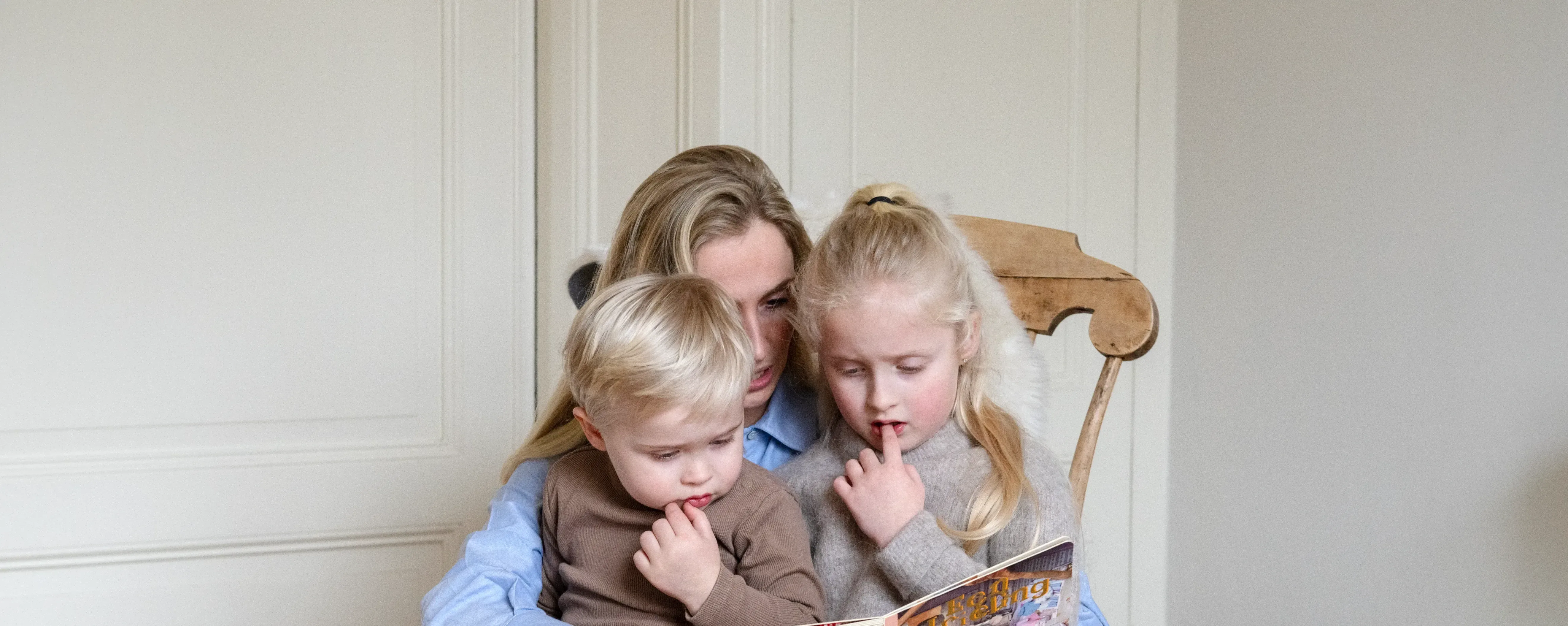 Moeder met dochter en zoon boekje aan het lezen in wipstoel