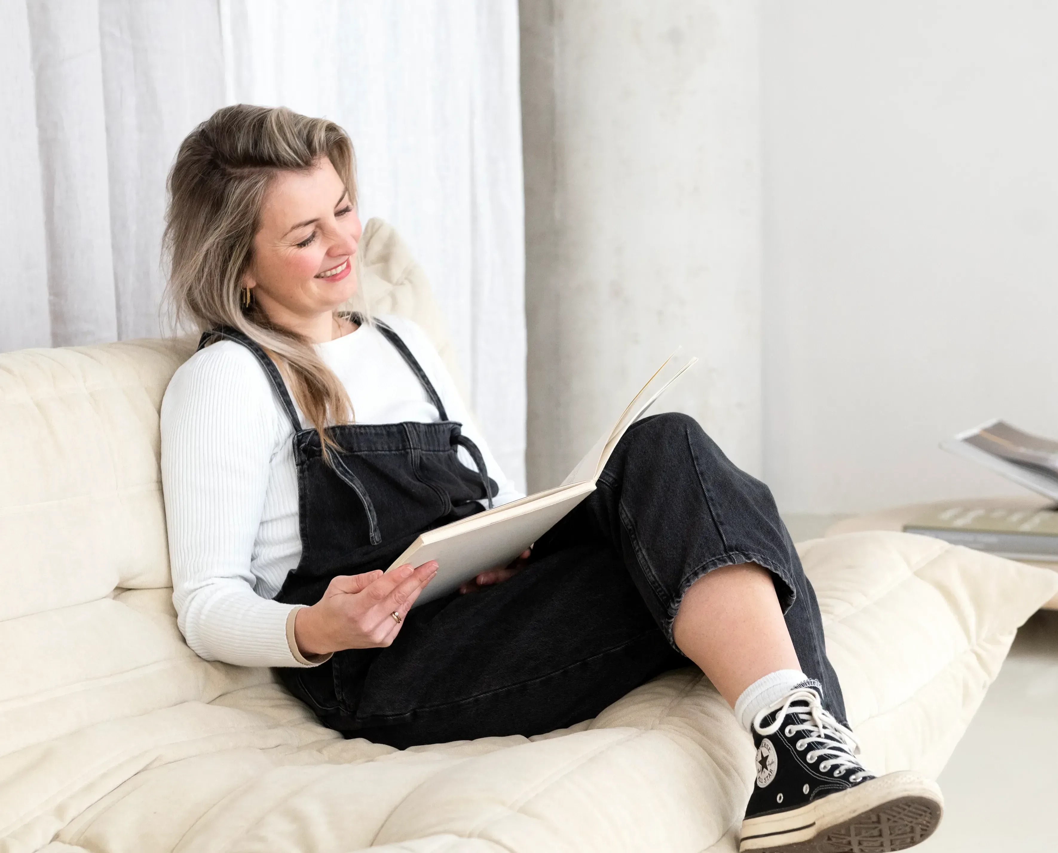 Vrouw zit op bank en leest tijdschrift