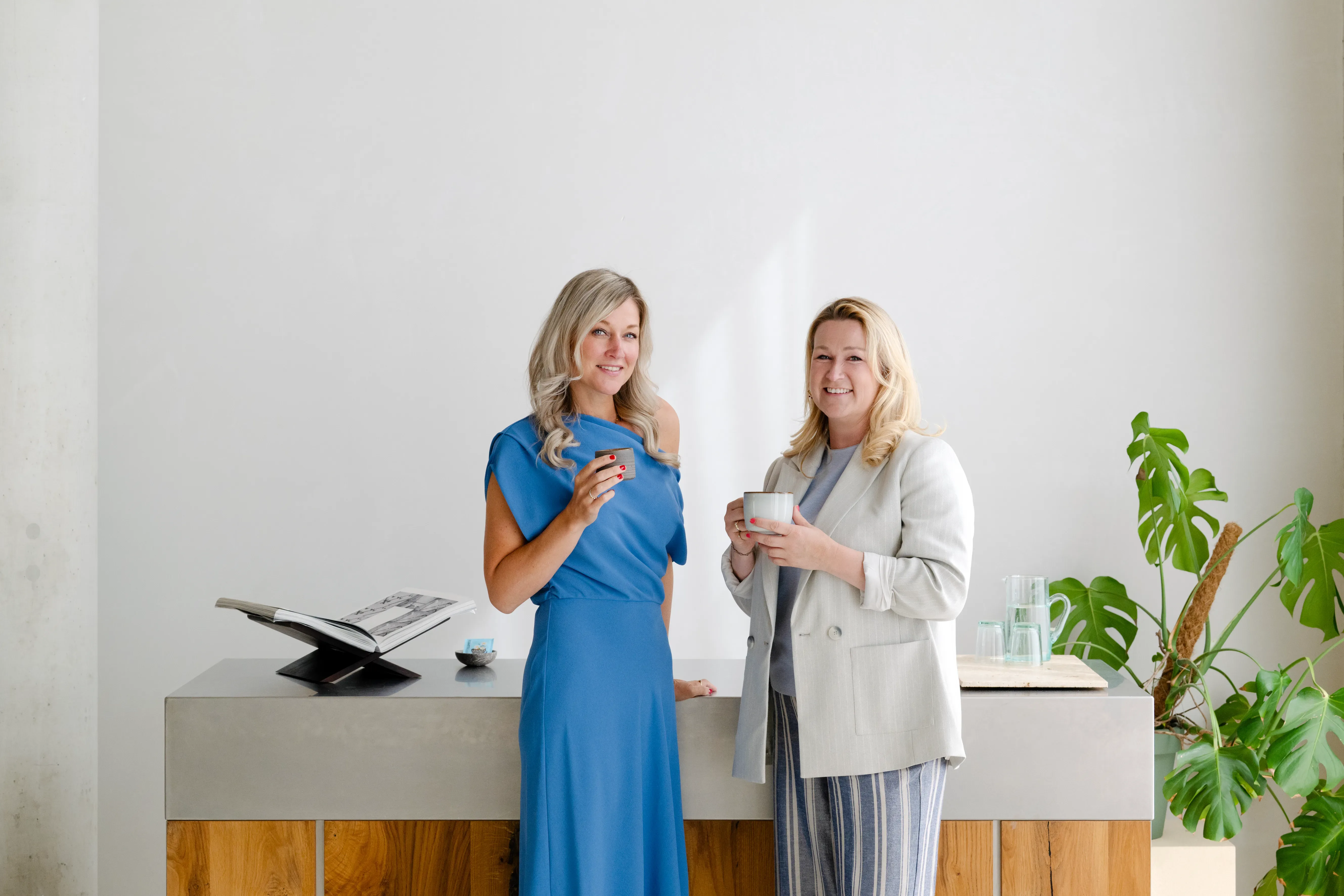 Twee vrouwen hebben kopje in hand en lachen naar camera