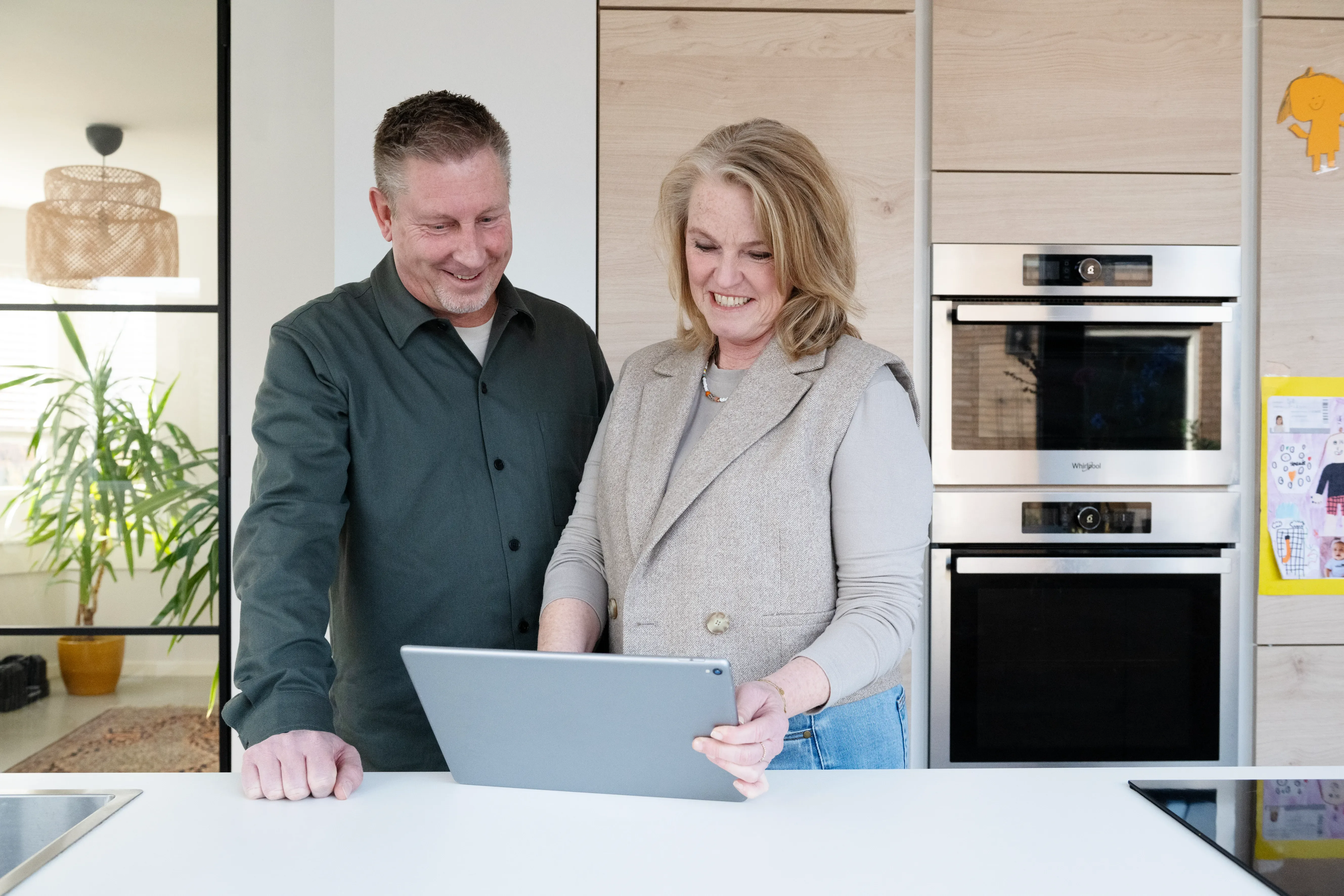 Man en vrouw staan achter tafel en kijken naar tablet scherm