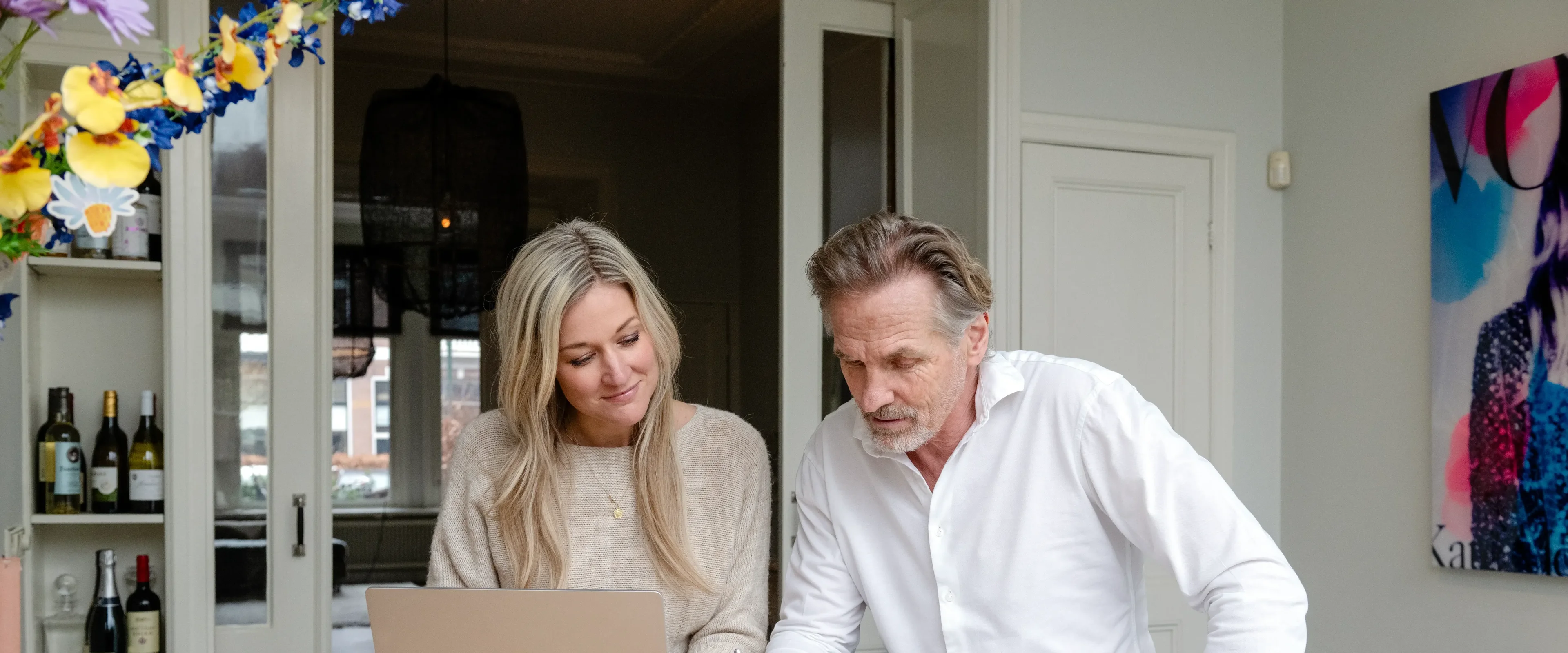 Man en vrouw zitten aan tafel en kijken naar laptop