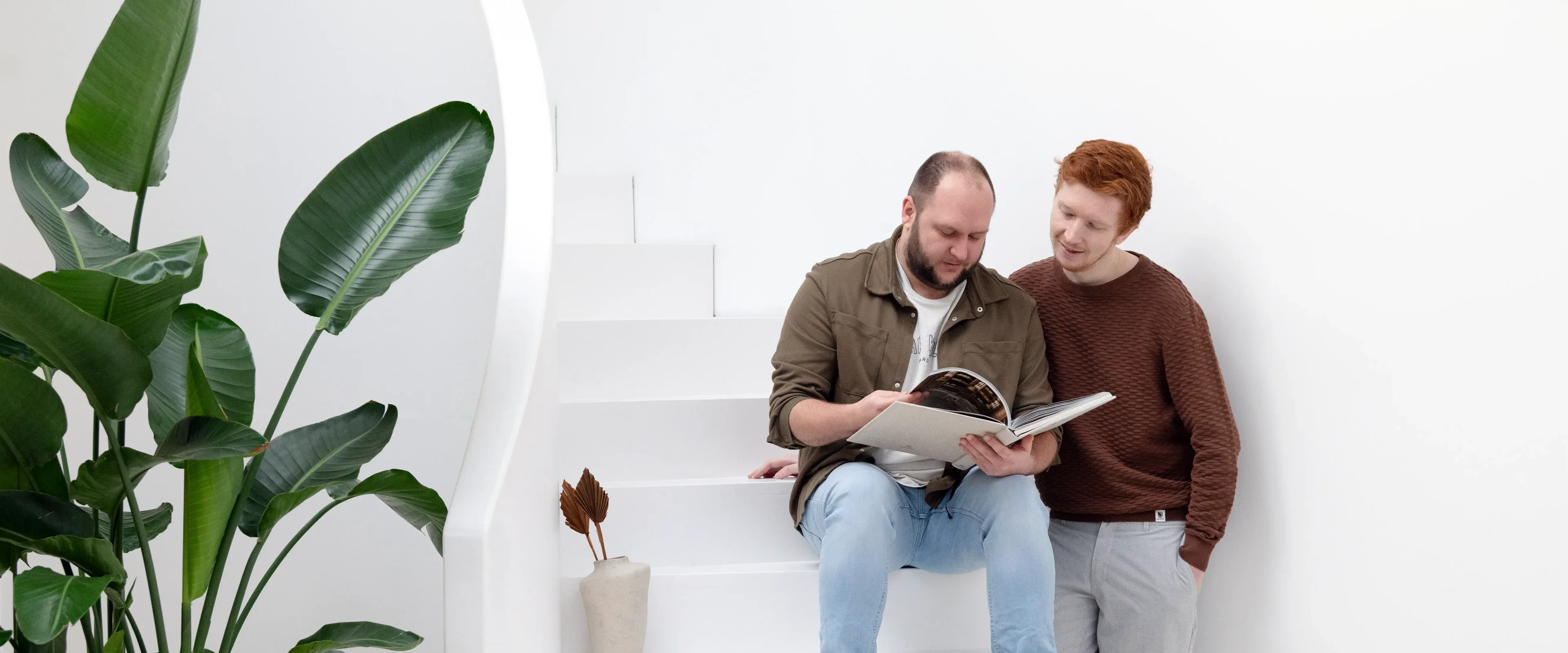 Twee mannen zitten op trap een boek te lezen