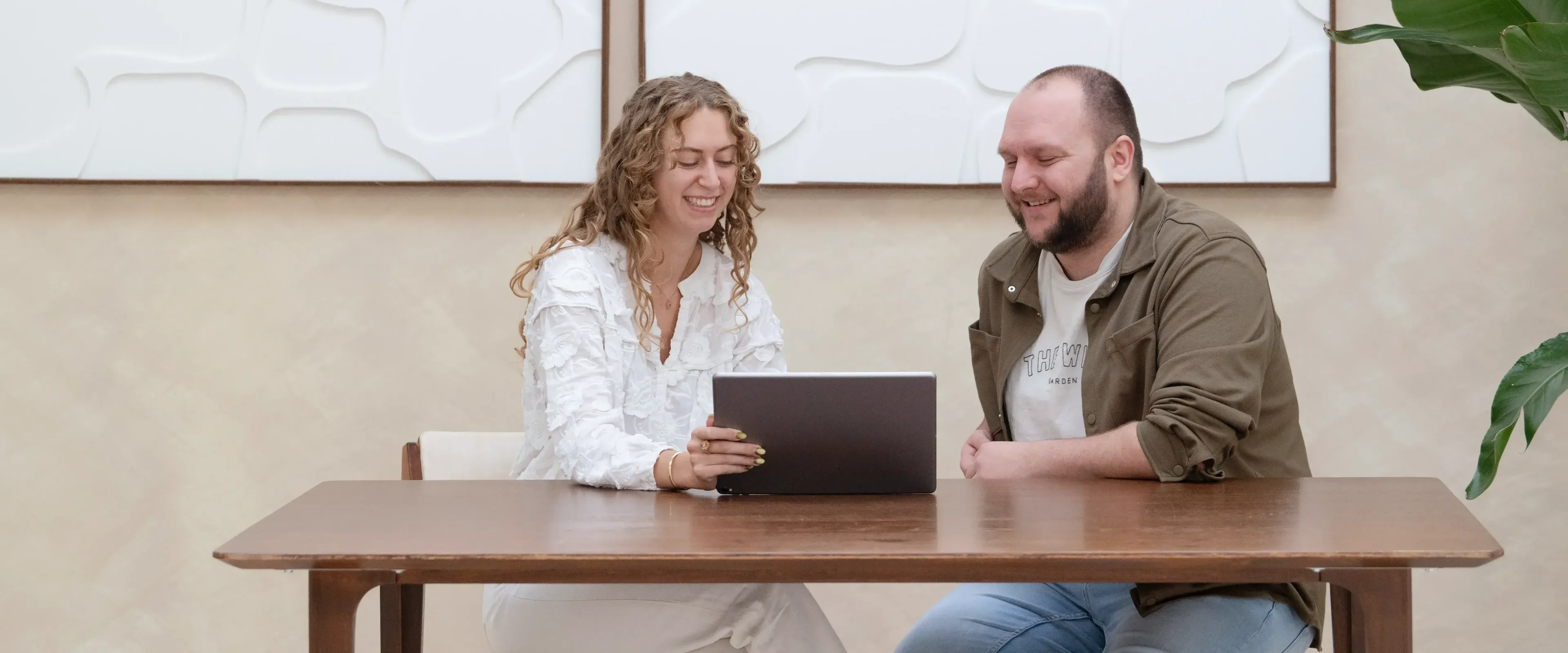 Man en vrouw aan tafel kijkend naar laptop