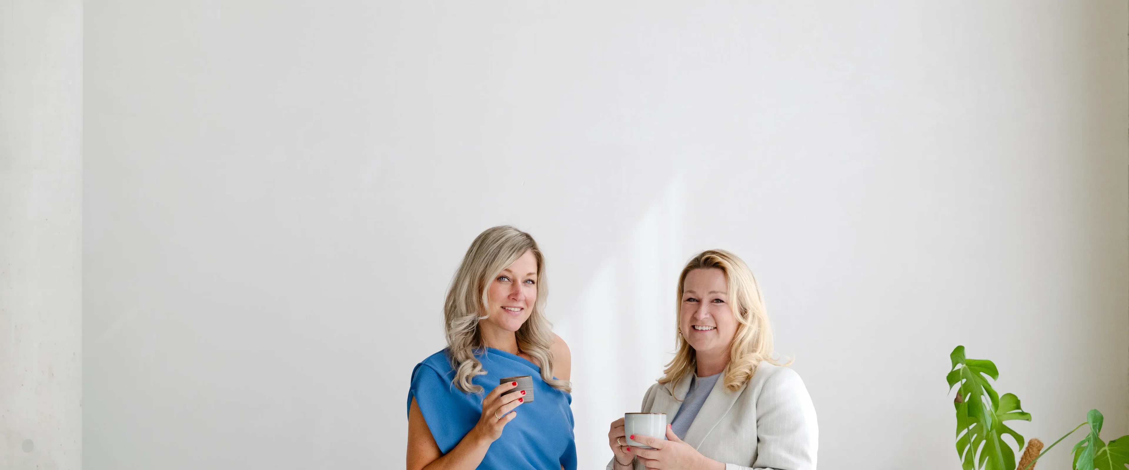 Twee vrouwen hebben kopje in hand en lachen naar camera