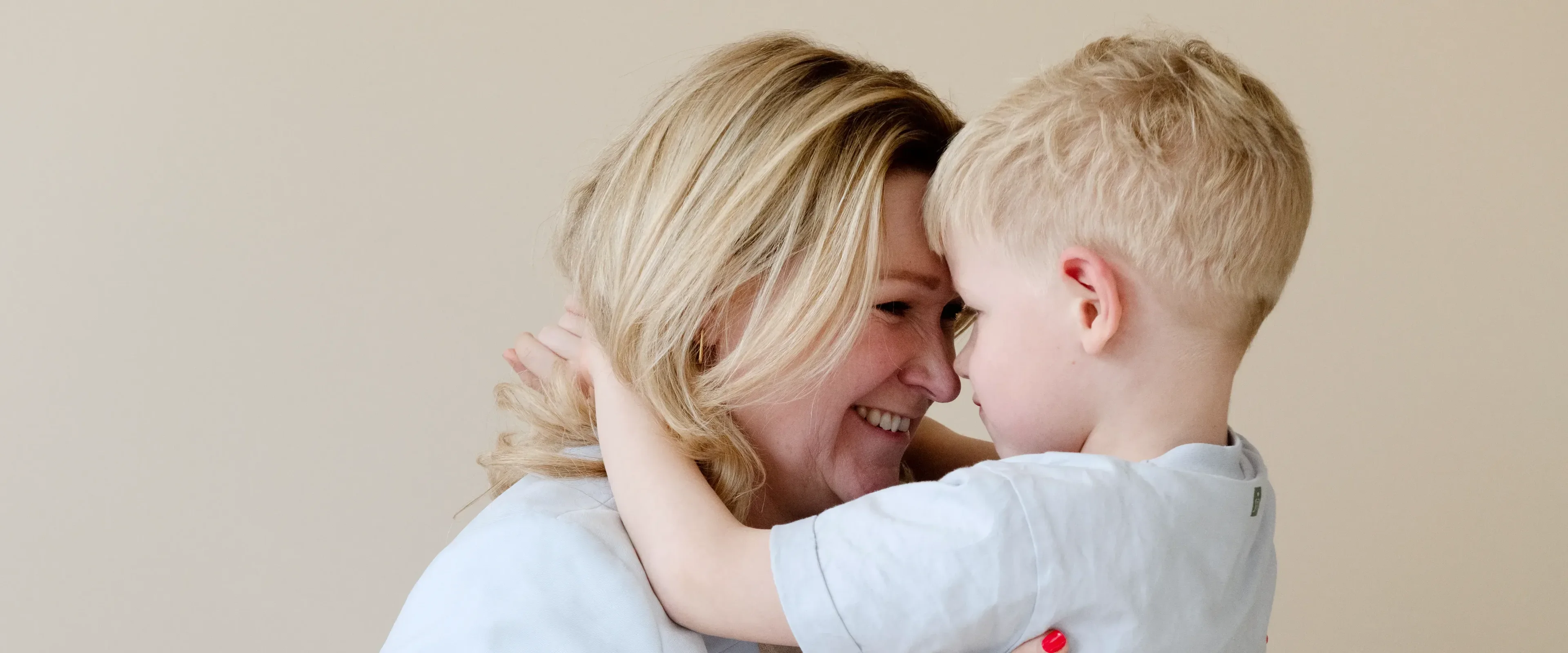 vrouw en zoontje knuffelend met hoofd tegen hoofd