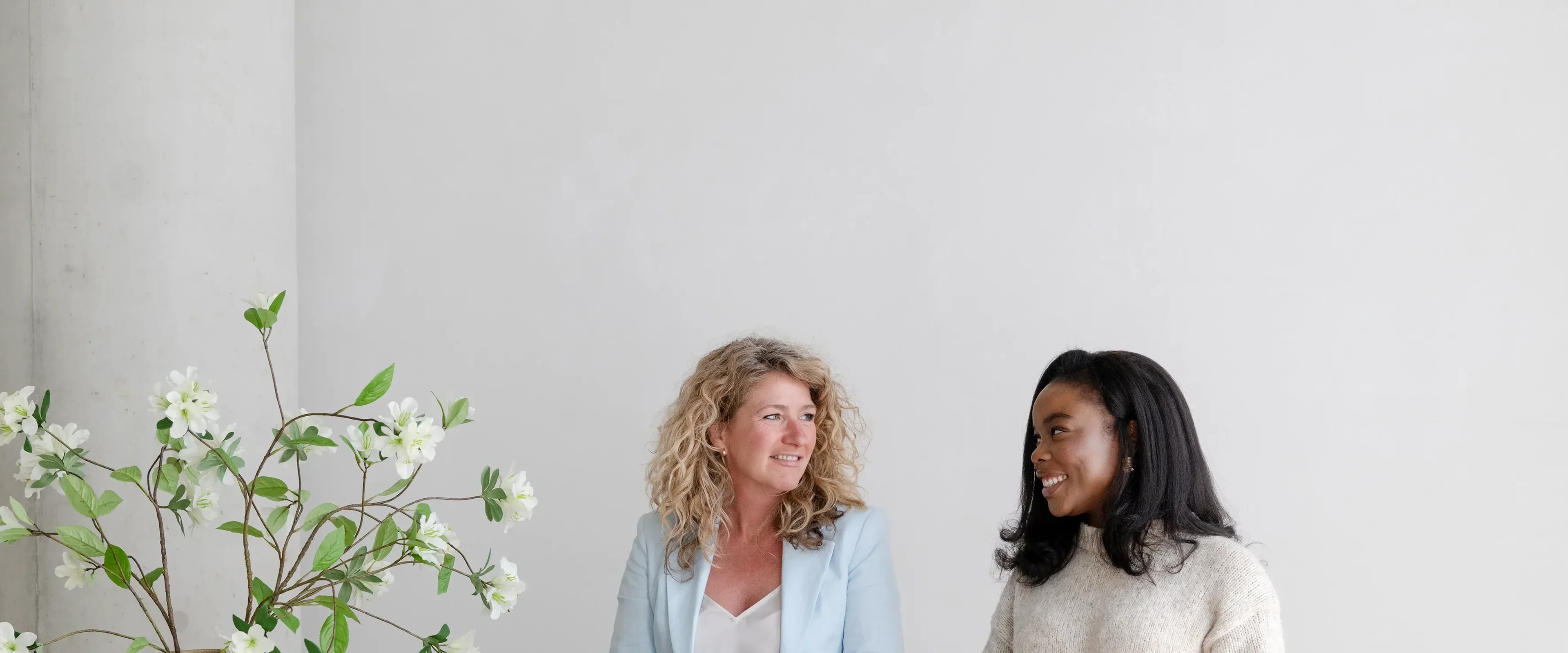 Twee vrouwen staan achter laptop lachend naar elkaar
