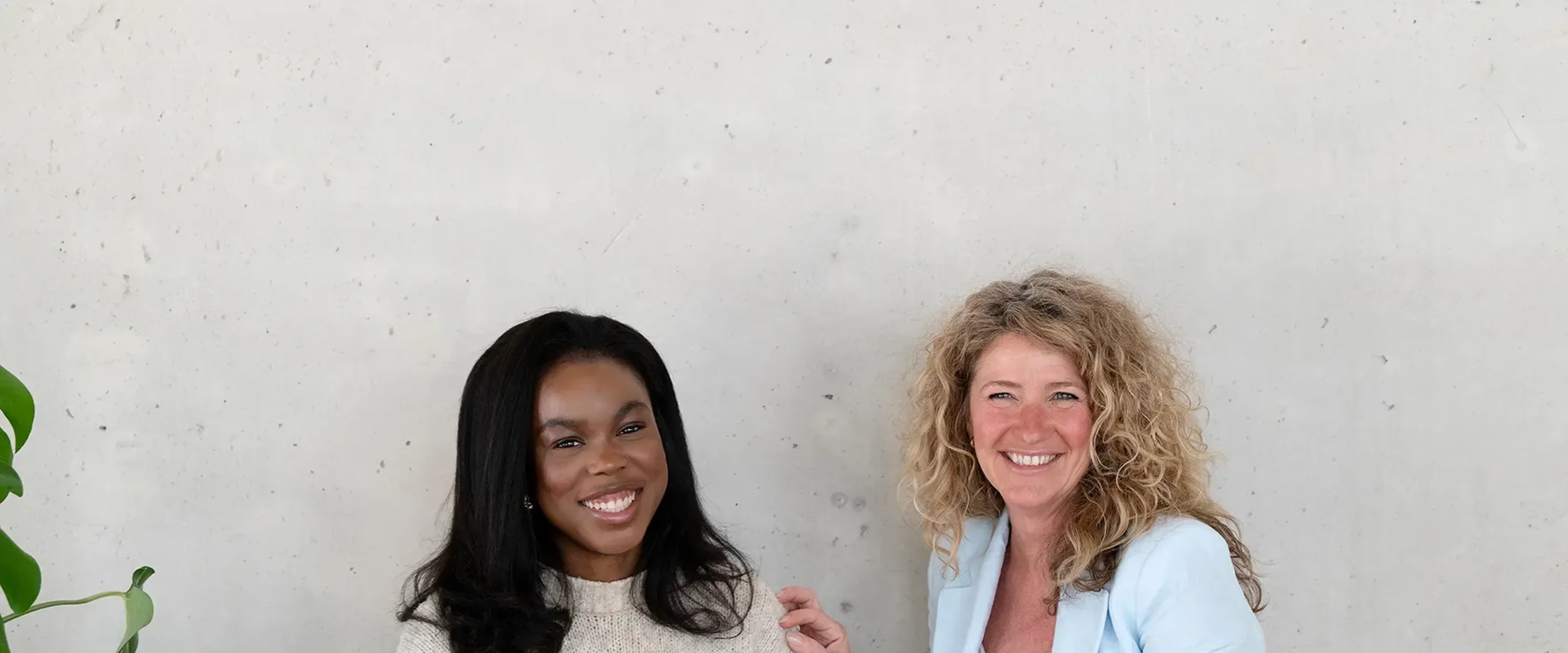 2 vrouwen aan tafel lachend naar de camera