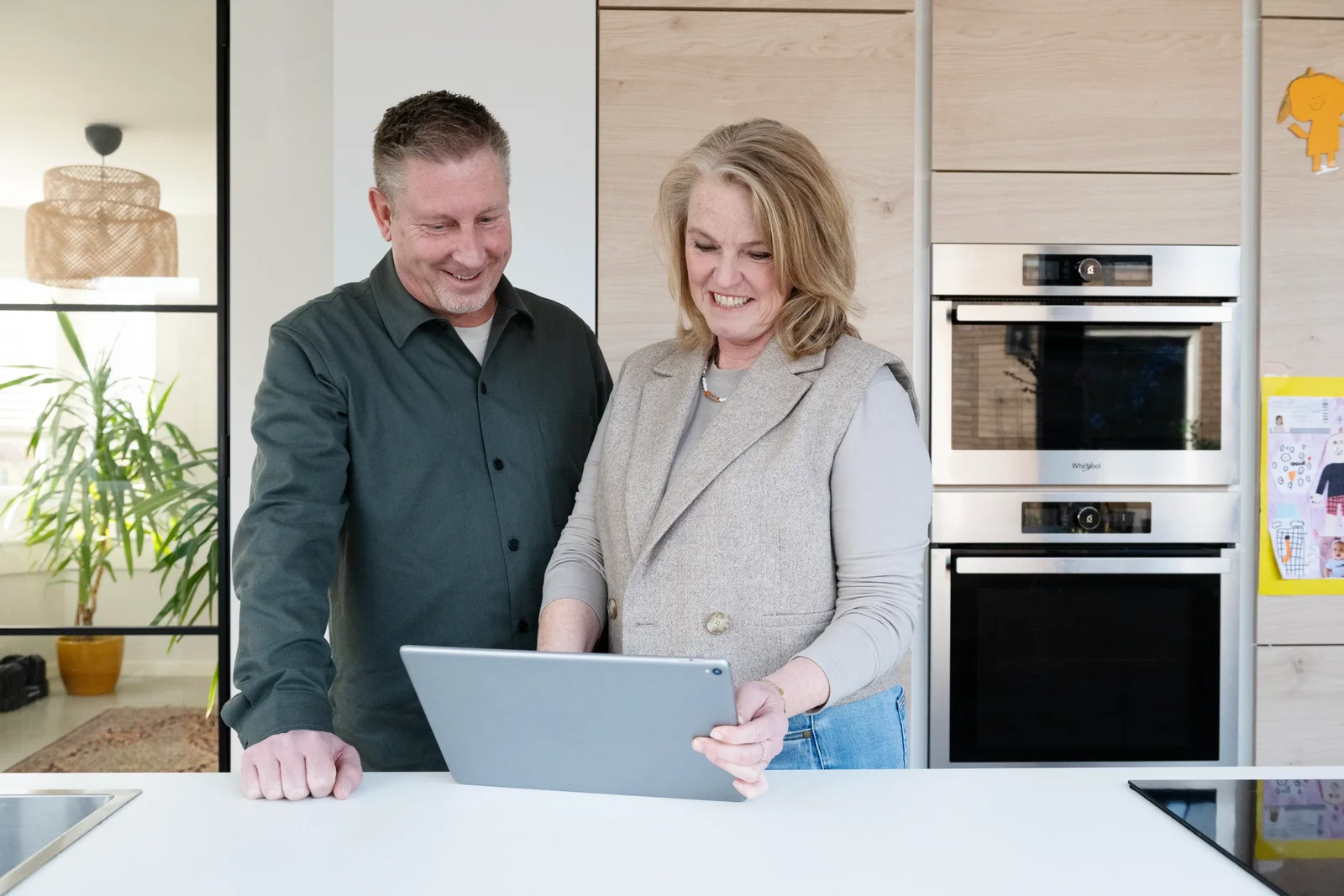 Man en vrouw staan achter tafel en kijken naar tablet scherm